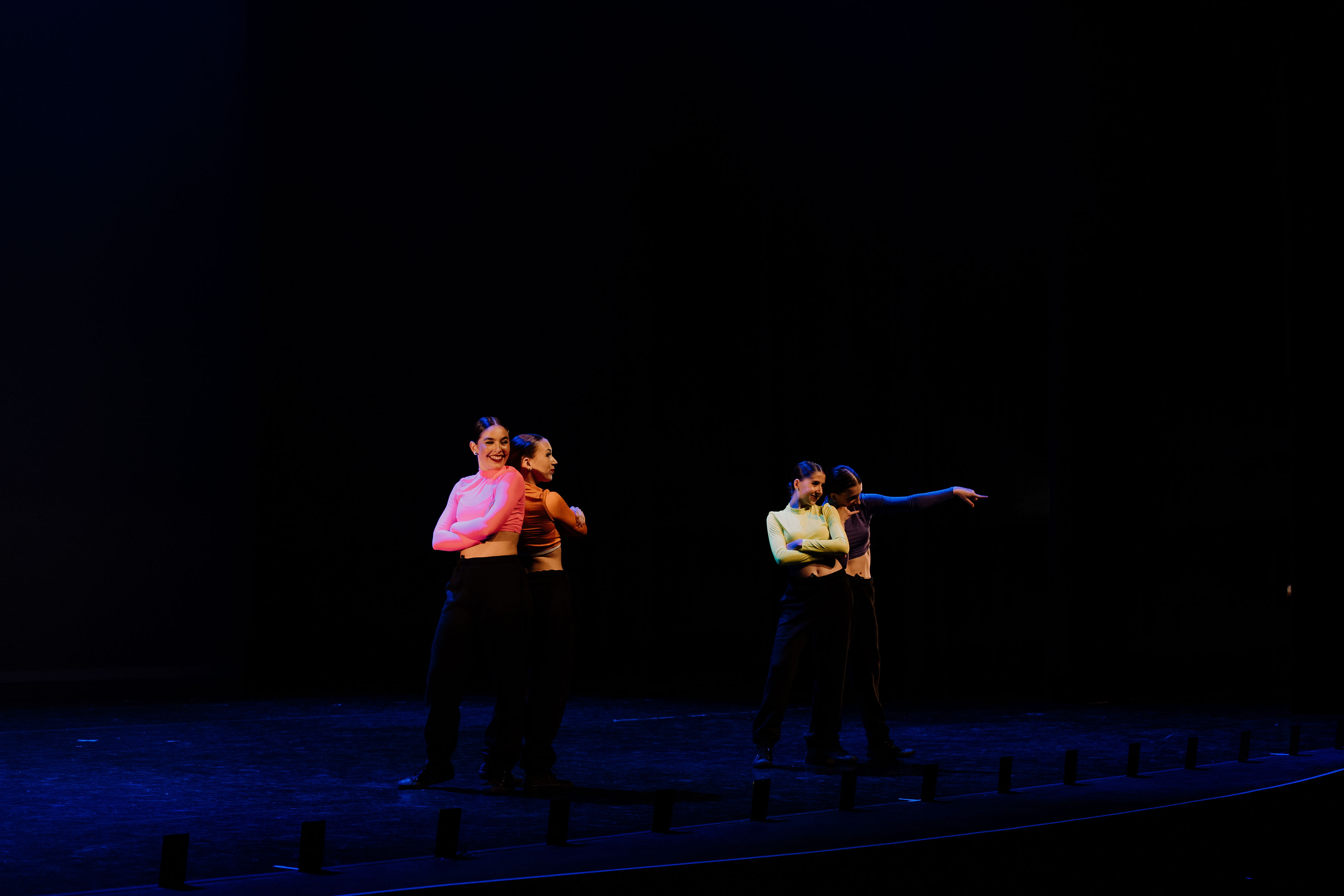 Four dancers performing a hip hop routine on stage
