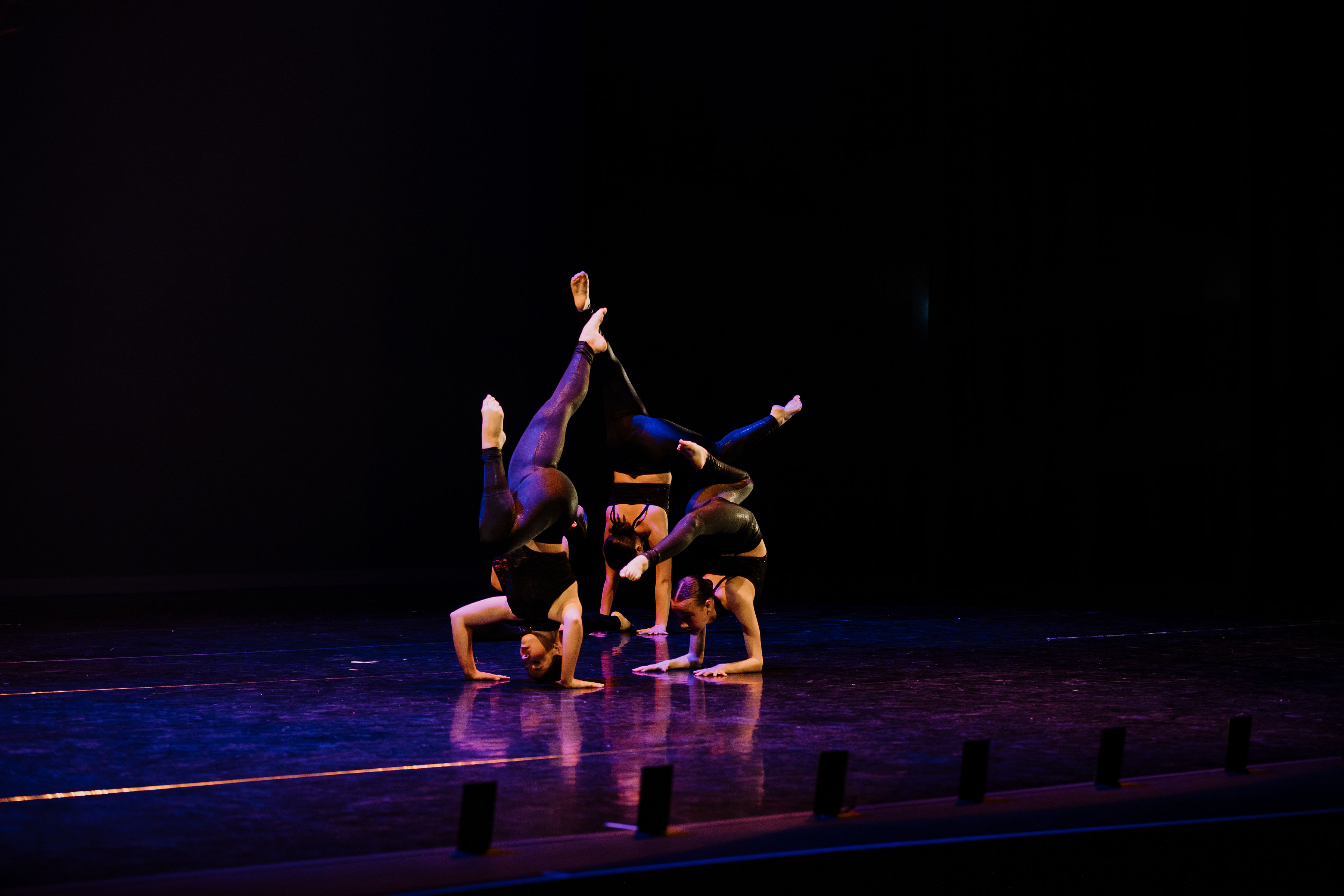 Three dancers in various Acro poses on stage