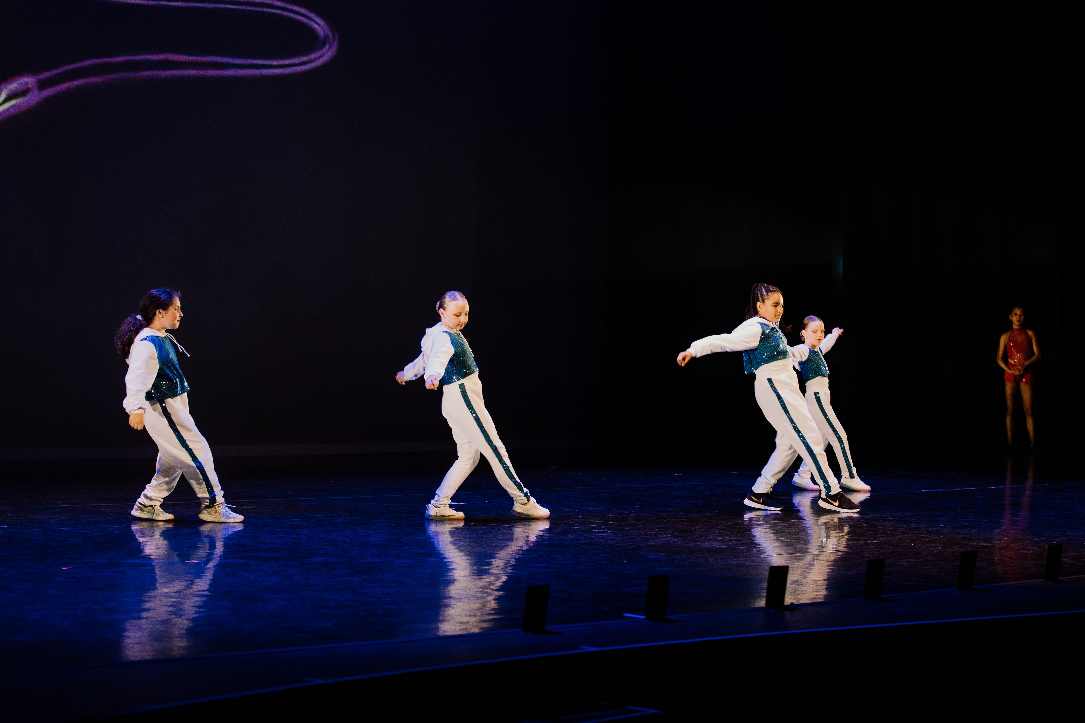 Four dancers performing a hip hop routine on stage