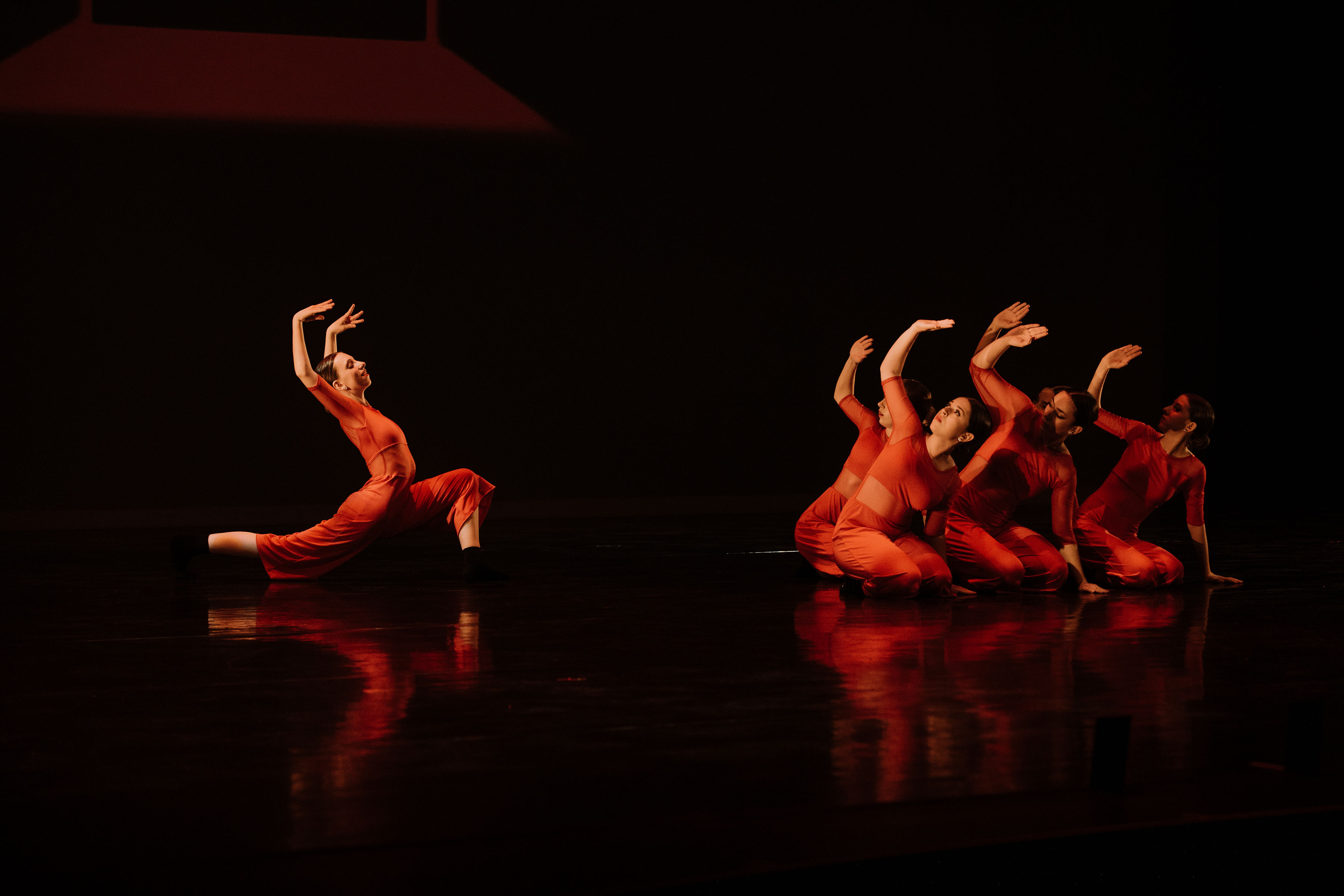 Contemporary dancers performing in all red costumes on stage