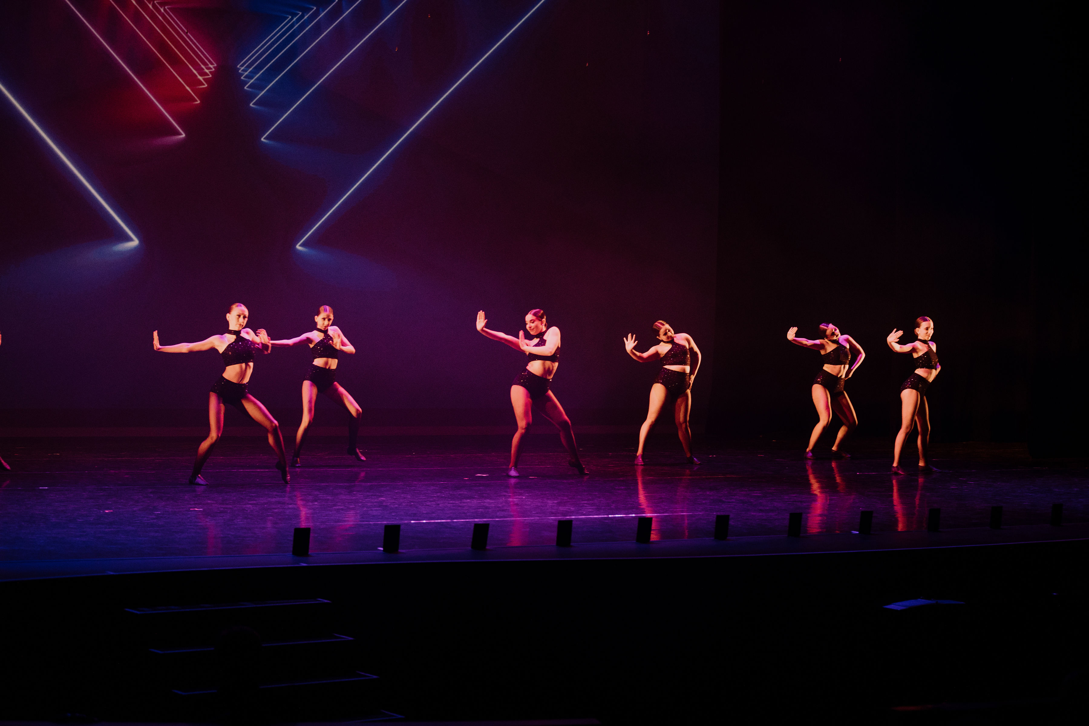 Six dancers performing jazz routine on stage