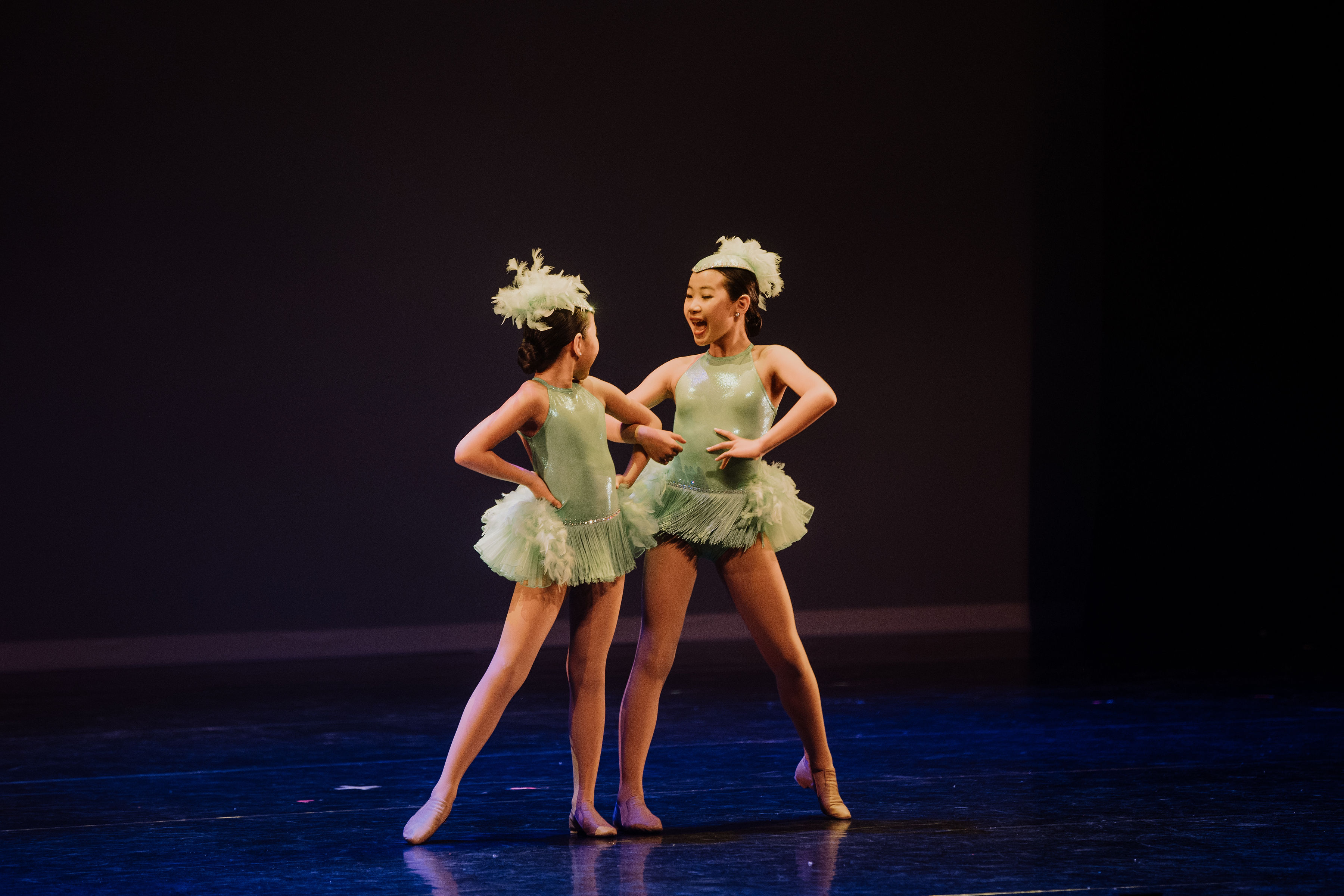 Two jazz dancers smiling at each other on stage